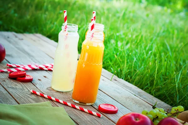 Succo diversi colori bottiglie frutta tavolo di legno — Foto Stock