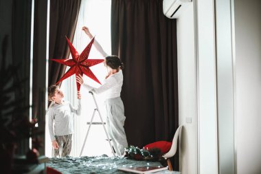 Anne ve oğul Noel için evlerini ve pencerelerini kızıl yıldızlı kış tatillerinin büyüsüyle dekore ediyorlar.