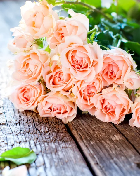 Kytice růžových růží na dřevěný stůl — Stock fotografie