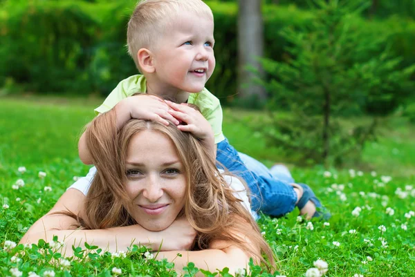 Fröhlich lächelnde Mutter und Junge, die auf ihrem Rücken spielen — Stockfoto