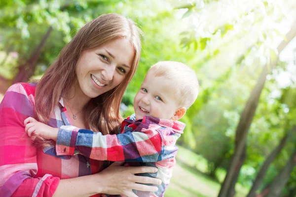 Glückliche Mutter und Sohn in ähnlichen Hemden, Jeans. Sommerpark — Stockfoto