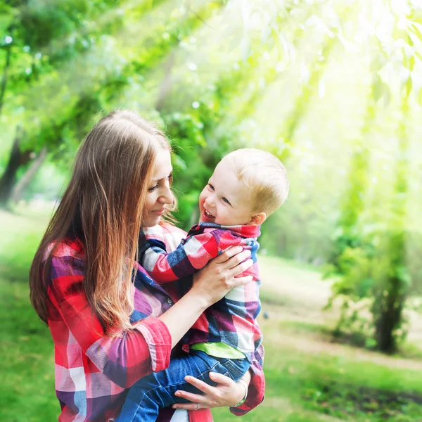 Mor med pojke leker i parken. Solljus effekter — Stockfoto