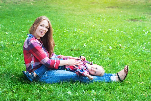Madre jugando con su hijo, sentada sobre hierba verde —  Fotos de Stock