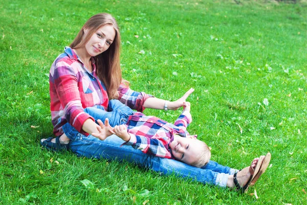 Sonriente madre jugando con su hijo en verde hierba — Foto de Stock