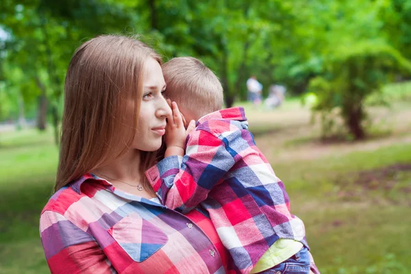 Junge Mutter hält ihren Sohn im Sommerpark an den Händen — Stockfoto