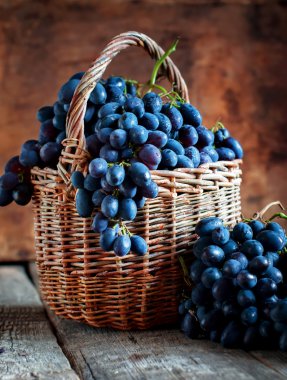 Kırsal sepeti ahşap zemin üzerine mavi üzüm