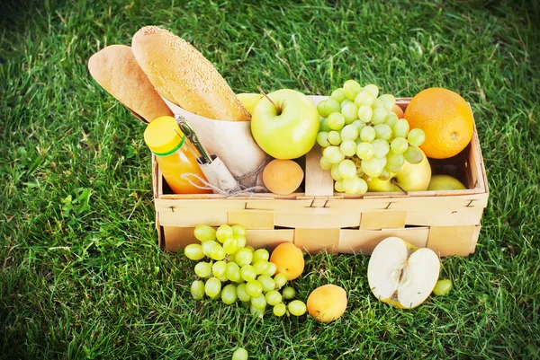 Comida fresca de verano en la cesta de picnic sobre hierba verde — Foto de Stock