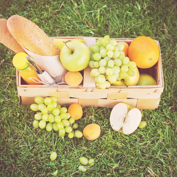 Cosecha en hierba verde, comida de picnic en la cesta — Foto de Stock