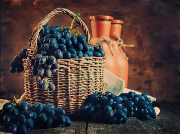 Uvas azules en la cesta rural sobre fondo de madera — Foto de Stock