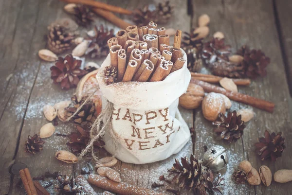 Ingredienti di Natale su sfondo di legno. Bastoni di cannella in sacchetto di lino ricamato con felice anno nuovo — Foto Stock