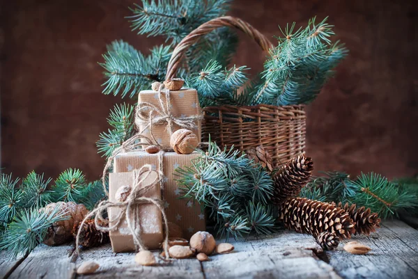 Regalos de Navidad. Cajas, Coníferas, Conos de pino, Abeto, Cesta, Nueces, Almendras sobre fondo de madera oscura — Foto de Stock