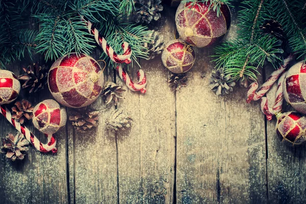 Juguetes de abeto vintage de Navidad, bolas rojas, coníferas, bastón de caramelo, conos de pino en tablones de madera. Tonificado —  Fotos de Stock