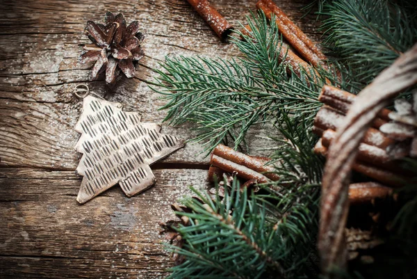 Ročník vánoční kovové jedle strom hračku, šišky, skořice, větve jehličnanů na dřevěný stůl — Stock fotografie