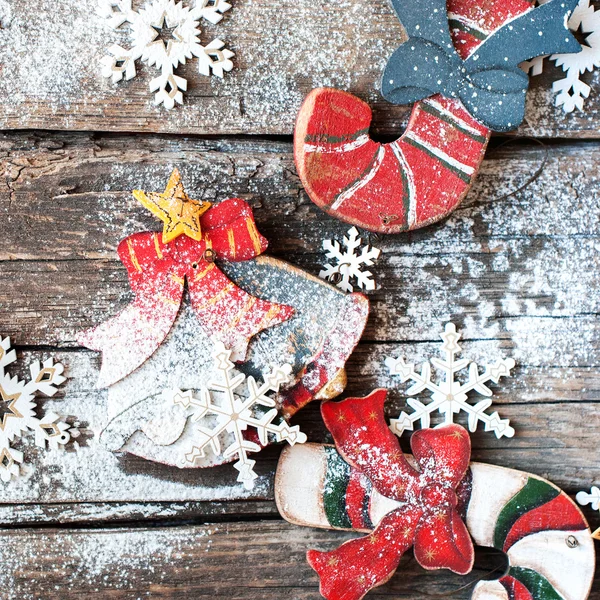 Urlaubstannen aus Holz spielen Zuckerstangen, Glocken und Schneeflocken auf dem Schreibtisch. Mit Schnee dekoriert. quadratisches Bild — Stockfoto