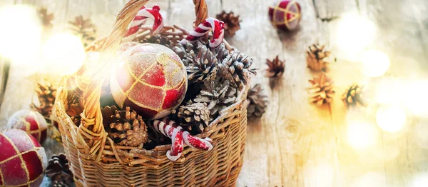 Bright Light Spots como efecto festivo con juguetes de abeto de Navidad en la cesta, bolas rojas, conos de pino — Foto de Stock