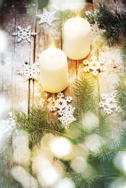 Christmas Light with Bokeh and White Burning Candles on Wooden Background