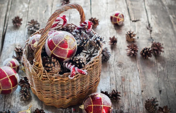 Presentes de Natal vintage na cesta, bolas vermelhas, cones de pinheiro, brinquedos doces — Fotografia de Stock