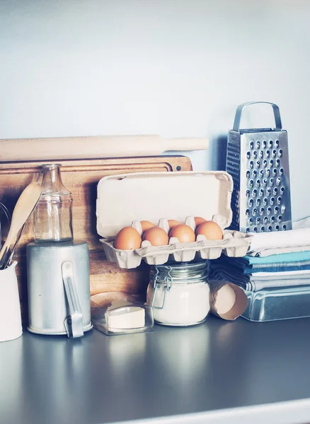 Ovos, louça de mesa, mercearia, coisas diferentes na mesa de cozinha. Imagem tonificada — Fotografia de Stock