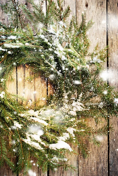 Grinalda natural verde com neve em fundo de madeira. Queda de neve é desenhada — Fotografia de Stock