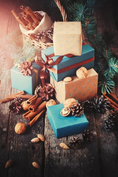 Regalos festivos con cajas, coníferas, cesta, canela, conos de pino, nueces al estilo vintage — Foto de Stock