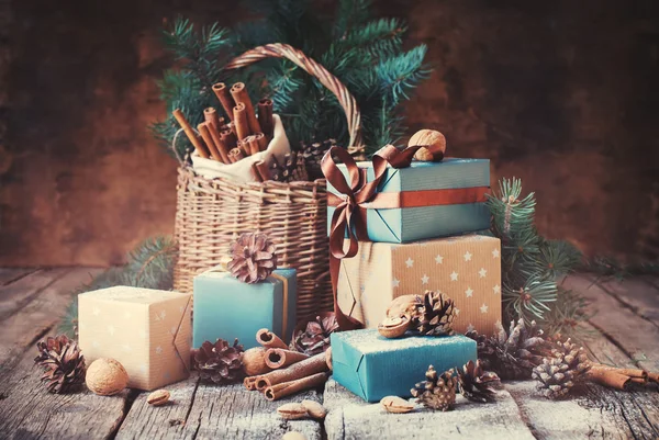 Cadeaux de fête avec boîtes, Conifères, Panier, Cannelle, Cônes de pin, Noix de Grenoble sur fond en bois — Photo