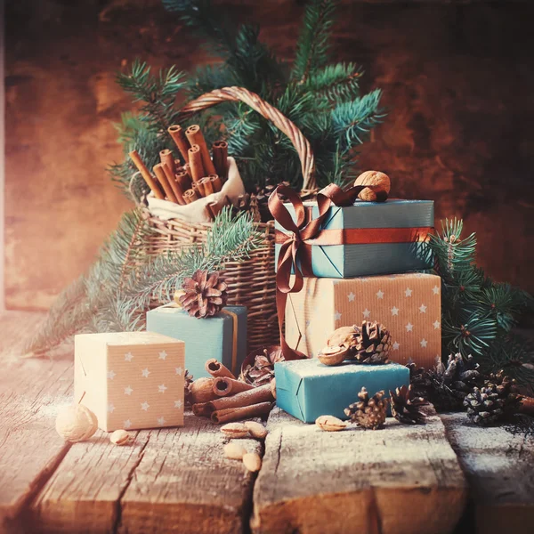 Regalos festivos con cajas, coníferas, canasta, canela, conos de pino, nueces. Tonificado en estilo Vintage —  Fotos de Stock