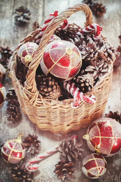 Presentes de Natal vintage na cesta rural. Bolas vermelhas, doce doce, cones de pinheiro — Fotografia de Stock