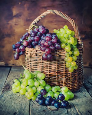 Ahşap arka plan üzerinde üzüm ile kırsal sepeti