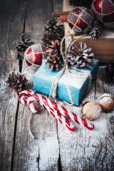 Boîte de vacances avec cadeaux et ficelle naturelle, boules, cônes de pin, noix, sapin jouets sur fond en bois. Style vintage — Photo