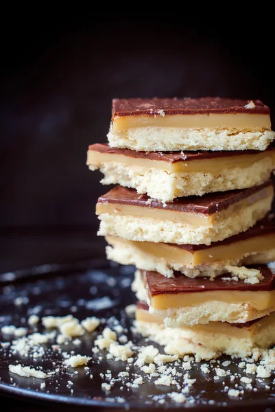Stapel chocolade koekjes met karamel op zwarte Tray — Stockfoto
