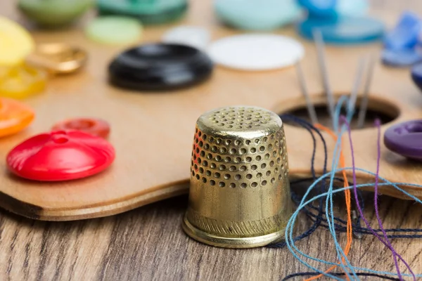 Buttons, thimble, needle and thread on the palette — Stock Photo, Image