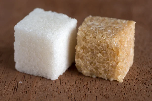 Cubos de azúcar moreno y blanco a bordo de caoba — Foto de Stock