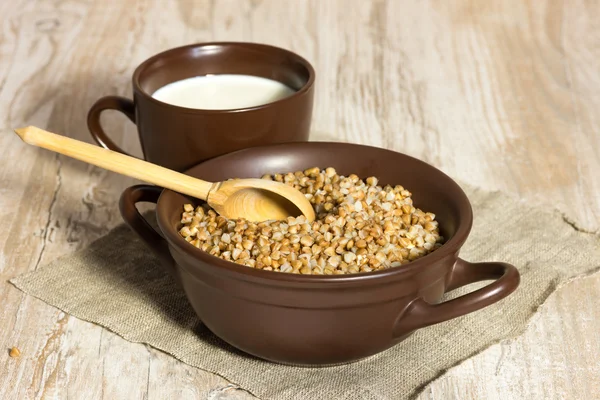 Buckwheat cereal, milk and wooden spoon — Stock Photo, Image