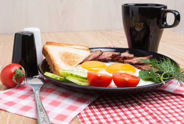 Fried eggs with bacon on black dish — Stock Photo, Image