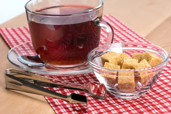 Hnědý třtinový cukr a šálek čaje — Stock fotografie