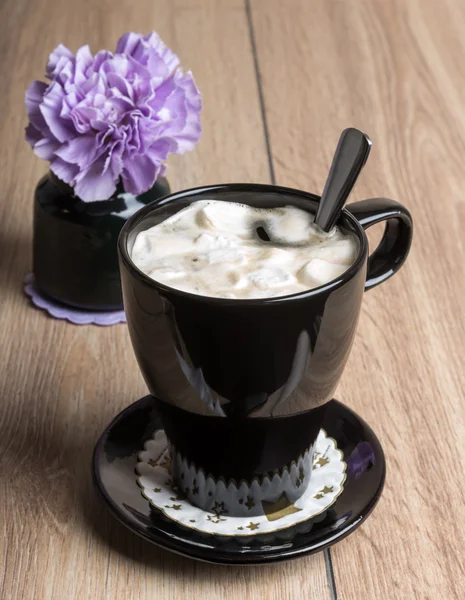 Coffee with marshmallows in a black mug and flower — Stok fotoğraf