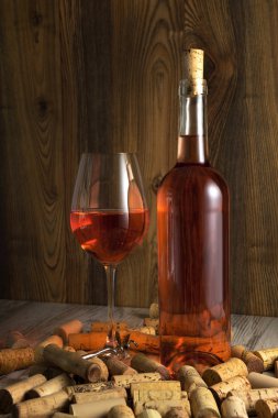 Rose wine in a transparent bottle, glass, cork and a corkscrew clipart