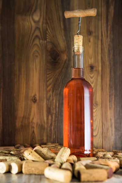 Рожеве вино в прозорій пляшці, пробці і шпорі — стокове фото