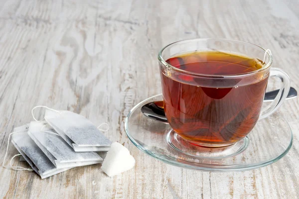 Bolsas de té y taza transparente con té — Foto de Stock