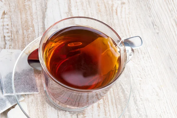 Bolsas de té y taza transparente con té — Foto de Stock