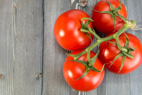 Rama con tomates maduros sobre una superficie de madera —  Fotos de Stock