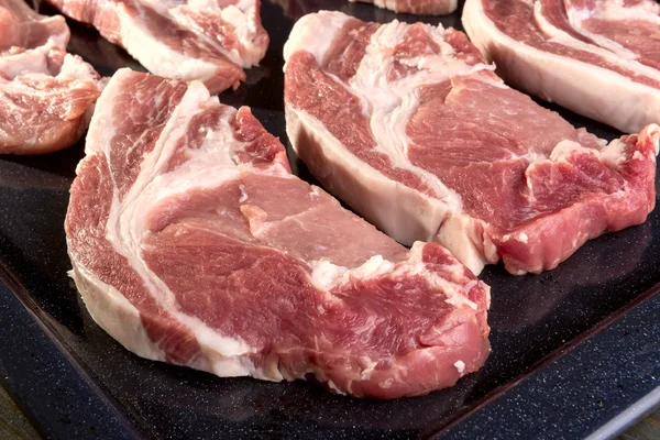 Куски свежего мяса свинины на хлебопекарном листе — стоковое фото