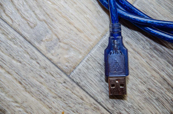 Short blue usb cable on wooden surface — Stock Photo, Image