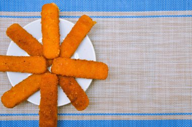 Beyaz bir tabakta kızarmış balık, gri bir arka planda.