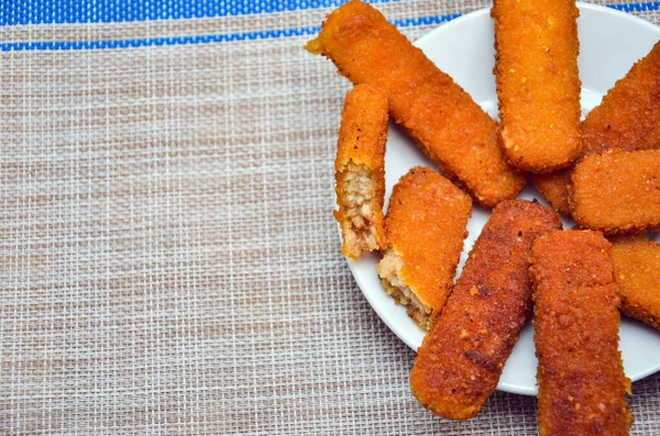 Beyaz bir tabakta kızarmış balık, gri bir arka planda.