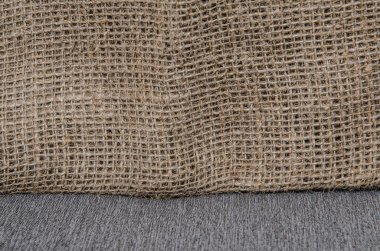 Beyaz çarşafta yatan kahverengi çuval bezi. Soyut arkaplan. Çuval bezi dokusu. Afişler için arka plan, ya da duvar kağıtları için. Rustik Hessian Çuval Kumaşı