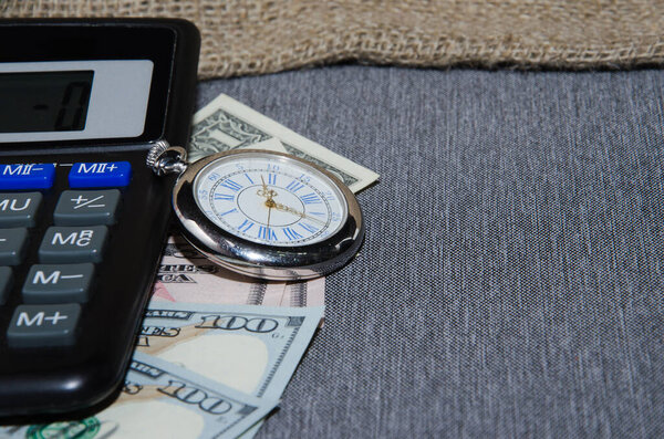 Калькулятор, ноутбук, деньги и будильник на деревянном столе, крупный план.