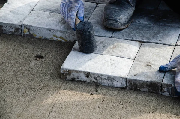 Evin yakınında asfalt inşaatı. Tuğlacı beton kaldırım taşlarını inşa etmek için yerleştirdi