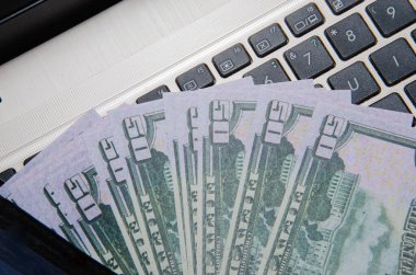 Diz üstü bilgisayar ve Amerikan doları, bilgisayar defteri ve dolar banknotları tahtadan bir arka planda, Amerikan doları banknotlu teknoloji,