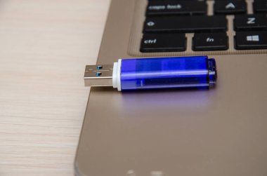 Mavi USB flaş bellek ya da dizüstü bilgisayara USB girişi. Not defteri açık gri bir masa arkasında. Veri depolama ve modern elektronik kavramı